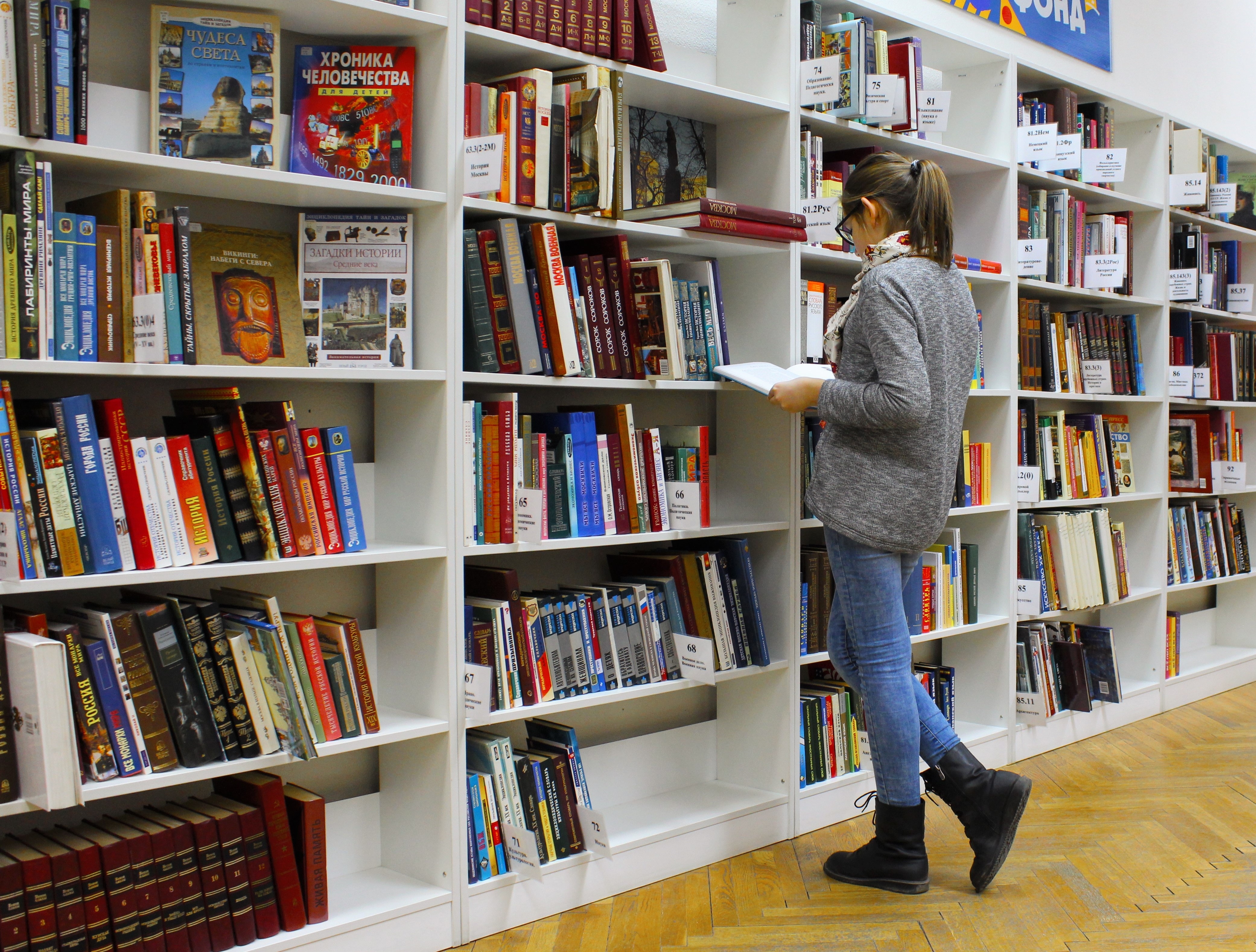 Student picking a book from a library shelf