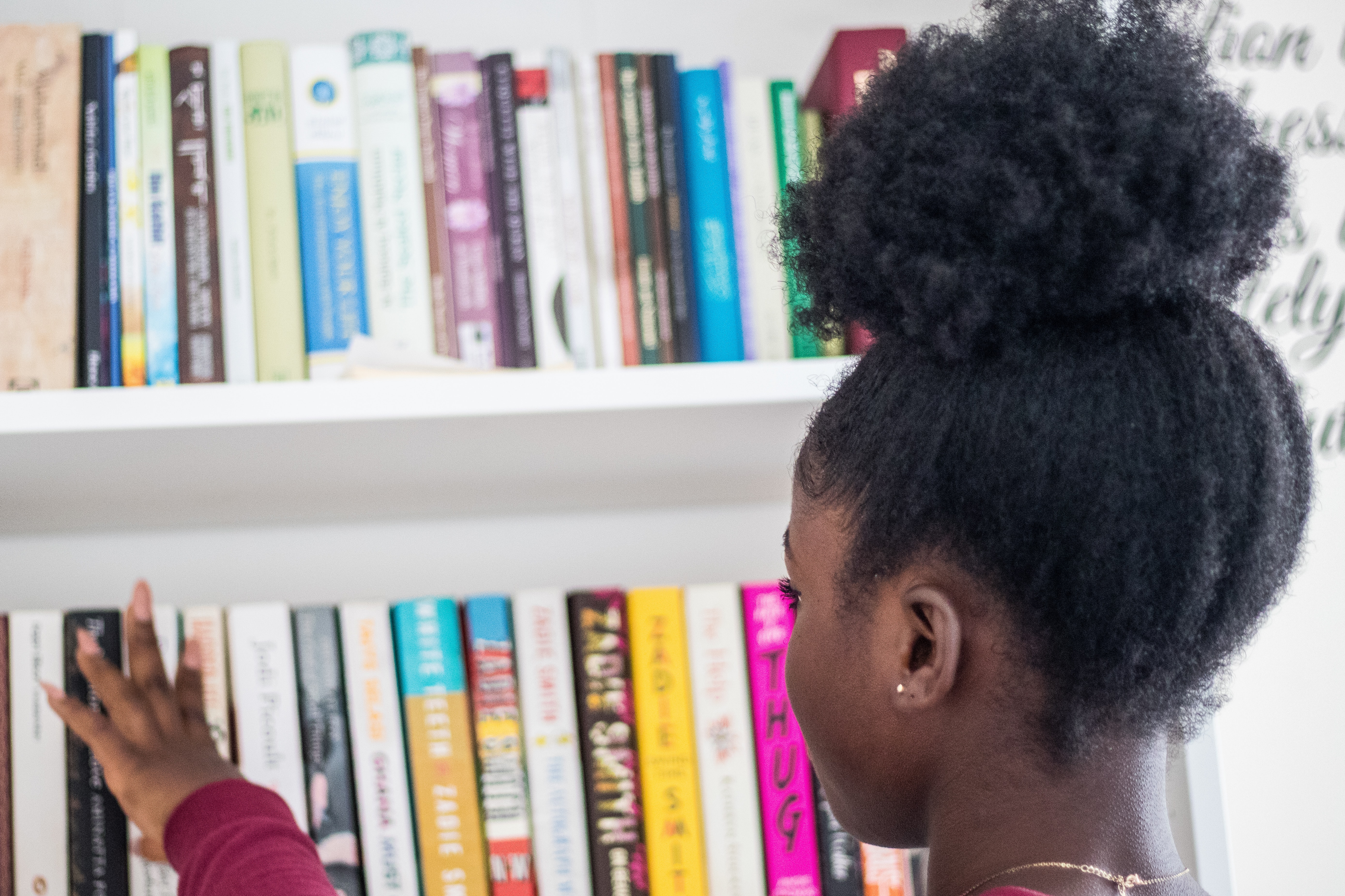 Student picking a book from a library shelf