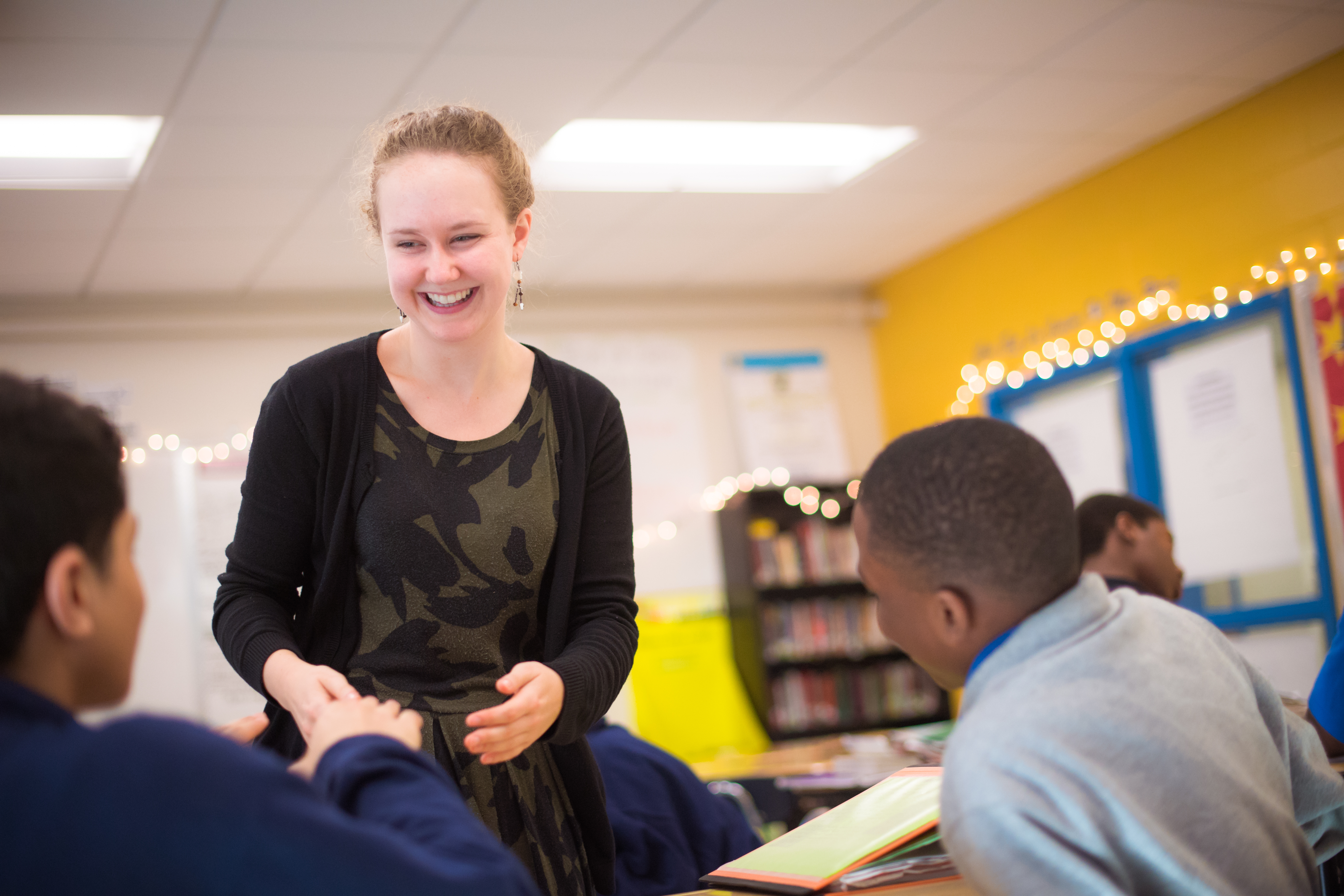 Teacher shaking a student's hand at their desk
