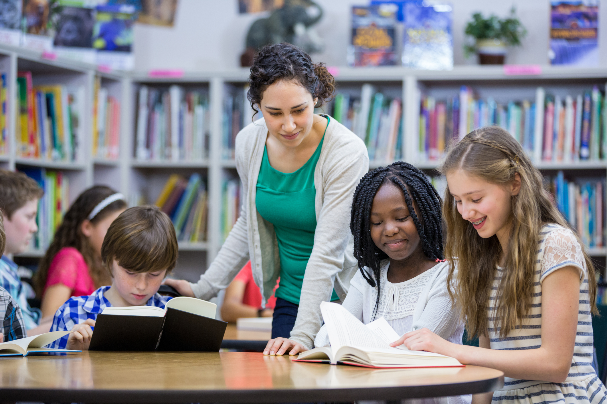 Teacher standing behind a table of students reading