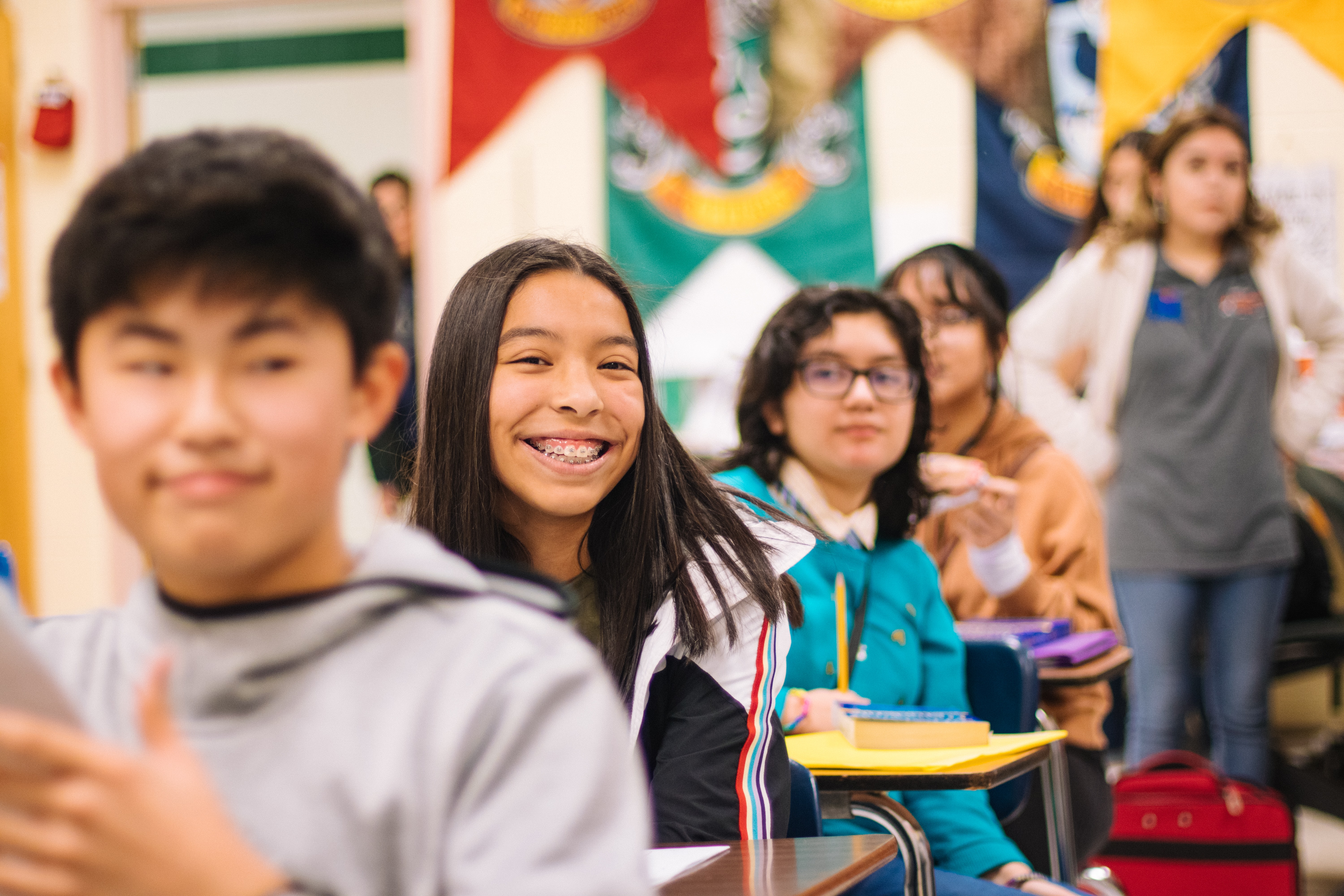 Student smiling at the camera from her desk